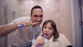 Oral health, happy father with child girl with toothbrush brushing teeth in front of mirror