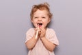 Oral hygiene. Dental care. Laughing funny little child baby brushing teeth isolated over gray background enjoying wearing t-shirt Royalty Free Stock Photo