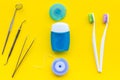 Daily oral hygiene for family. Toothbrush, dental floss and dentist instruments on yellow background top view