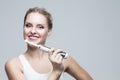 Oralcare and Dentistry Concepts. Caucasian Blond Woman Cleaning Teeth with Electric Toothbrush Posing Against Over Gray