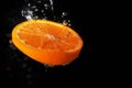 Orange slice in water with bubbles and black background