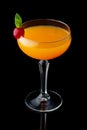 Orange alcohol cocktail with mint and cherry isolated on black