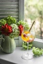 Orange alcohol ice cocktail and a bouquet of summer garden flowers in a vintage ceramic vase on the window on a summer day Royalty Free Stock Photo