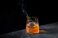 orange alcoholic cocktail with a sprig of pine needles and round ice, side view Royalty Free Stock Photo