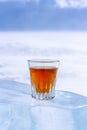 An orange alcoholic drink in a glass stands on an ice piece. Royalty Free Stock Photo