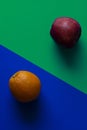 Orange and apple on blue and green background, minimalist photography