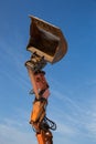 Orange arrow with excavator bucket against blue sky Royalty Free Stock Photo