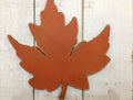 Orange artificial maple leaf on wood background