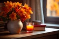 Orange autumnal flowers in vase and lit candle on wooden background