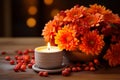 Orange autumnal flowers in vase and lit candle on wooden background