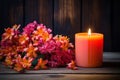 Orange autumnal flowers in vase and lit candle on wooden background