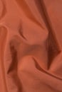 Orange background from crumpled, wavy fabric. Soft focus