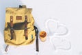 Orange backpack with leather elements and yellow thermos of hot tea or coffee on a background of white pure snow in winter mount