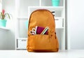 Orange backpack with school supplies on table indoors