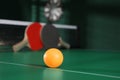 Orange ball on green ping pong table indoors. Space for text Royalty Free Stock Photo