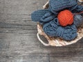 The orange ball of wool yarn and blue yarn in a wicker basket