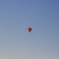 An orange balloon carries people balloonists tourists across the blue sky Royalty Free Stock Photo