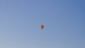 An orange balloon carries people balloonists tourists across the blue sky Royalty Free Stock Photo