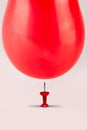 An orange balloon falls on a pin needle on white background