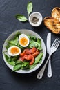 Delicious brunch - spinach, smoked salmon, soft boiled egg on a dark background, top view. Healthy eating diet Royalty Free Stock Photo