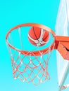 An orange basketball ball in hoop on a blue sky background. A ball flying into the basket. Side bottom view Royalty Free Stock Photo