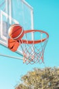 An orange basketball ball in hoop on a blue sky background. Side view Royalty Free Stock Photo
