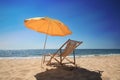 Orange beach umbrella and deck chair on sandy seashore Royalty Free Stock Photo