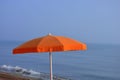 An orange beach umbrella in front of the sea