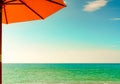 Orange beach umbrella on golden sand beach by the sea with emerald green sea water and blue sky and white clouds. Summer vacation Royalty Free Stock Photo