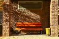 An orange bench under a brick canopy, illuminated by the autumn morning sun.