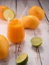 Orange beverage macro with lime slice on white vintage wooden desktop with mango Royalty Free Stock Photo