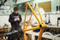 Orange bicycle frame held on a stand in a mechanical bike repair shop