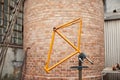 Orange bicycle frame held on a work stand in a mechanical bike repair shop