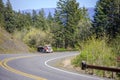 Orange big rig classic semi truck with oversize load sign on the roof transporting loaded tip trailer climbing uphill on the Royalty Free Stock Photo