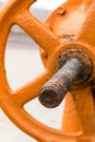 Orange big valve part of the gas pipeline system and oil production design industrial close-up with a long rusty base