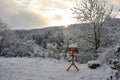 A orange bird house in front of a forest, at sunrise in winter with lots of snow Royalty Free Stock Photo