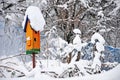 Orange birdhouse covered with snow