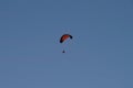 Orange black paraglider with fan in blue sky