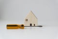 Orange-black screwdriver and small white wooden house. White background. Home improvement ideas