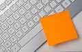 Blank sticky note pasted on keyboard at work table Royalty Free Stock Photo
