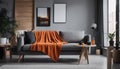 Orange blanket on grey sofa in modern apartment interior with poster and wooden table Royalty Free Stock Photo