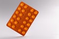 Orange blister with pills on gray background.