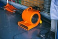 Orange blower fan machine on wet floor. Heavy Duty Industrial Portable Blower Fan on floor Used to reduce heat to racing cars.