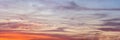 Orange and blue clouds on sunset lit sky, wide banner background that looks like painting Royalty Free Stock Photo