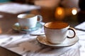 Orange and blue cups on saucers. The mugs with tea in soft focus standing on menu papers