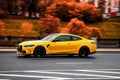 Orange BMW 4 Series coupe G22 is driving along the street with an autumn urban background Royalty Free Stock Photo