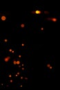 Orange bokeh on a black background, burning and blurred sparks from the fire. Particles of burning embers fly and glow isolated in Royalty Free Stock Photo