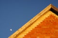 Orange brick house roof and growing moon in clear blue sky during the day Royalty Free Stock Photo