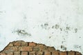 Orange bricks peeking out from under a white peeling wall. destroyed brick wall, painted with plaster and paint Royalty Free Stock Photo