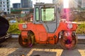 Orange bright asphalt paver with big wheels. metal gray roof, next to the windows. against the backdrop of the scorching bright